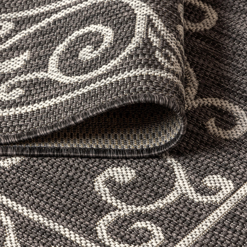 Close-up of rug corner edge showing black and gray woven texture with white pattern