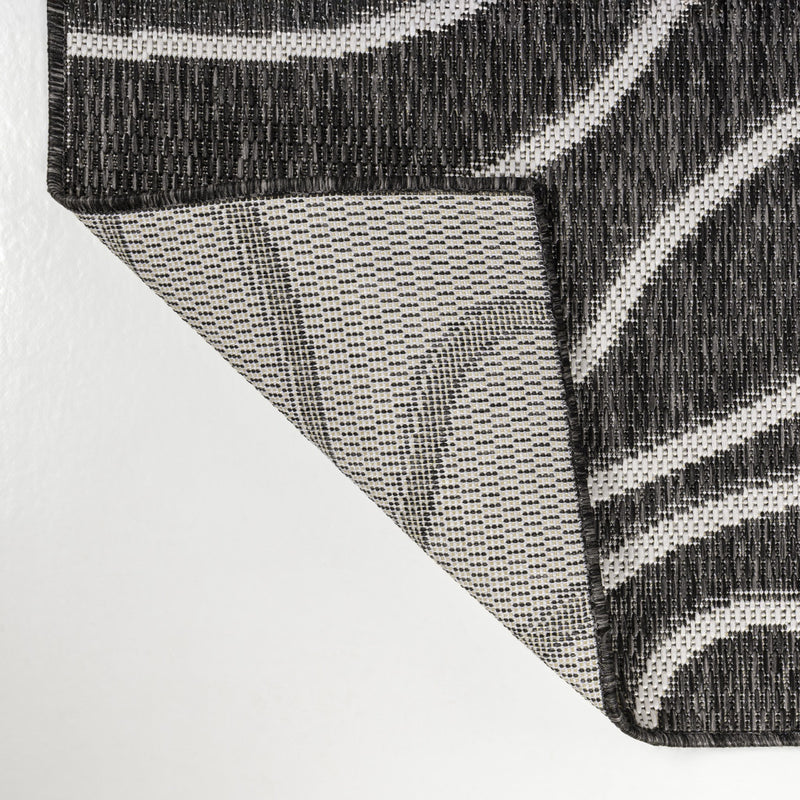 Corner detail of black and cream abstract area rug with woven backing view