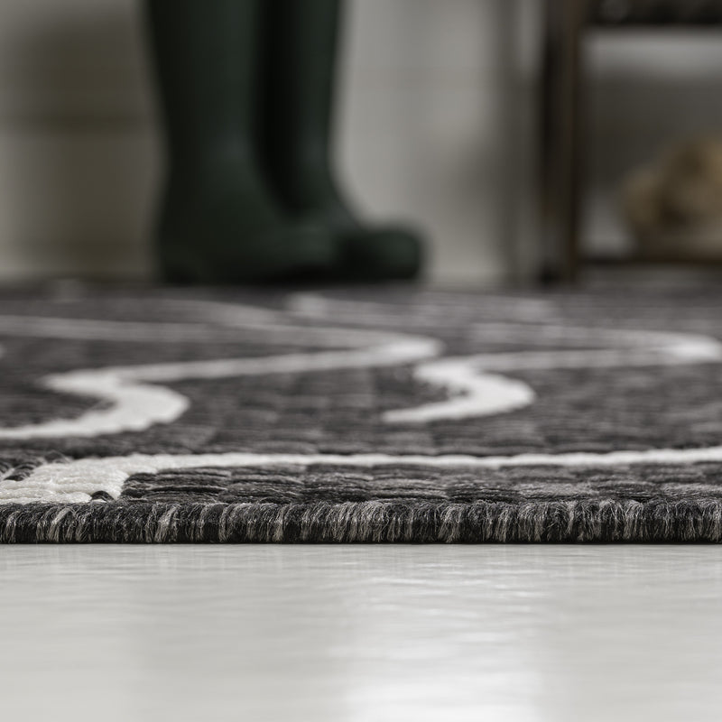 Black and cream abstract area rug edge with thin fringe, low pile close-up