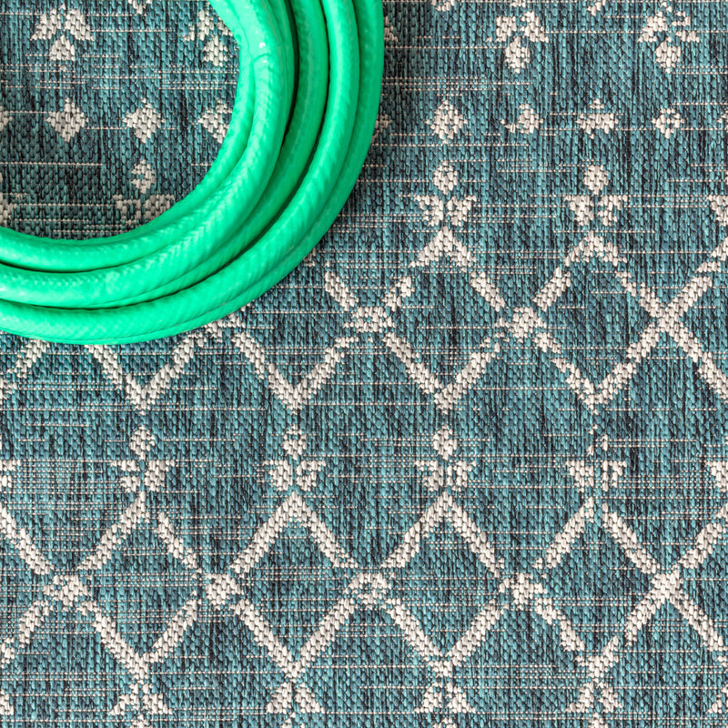 Teal blue area rug with white diamond trellis pattern and textured surface