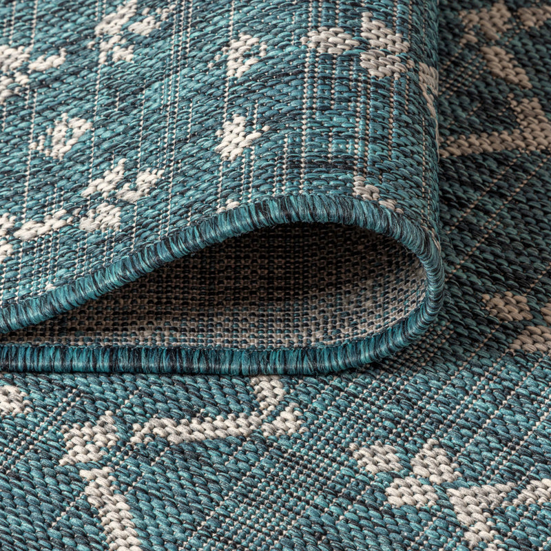 Teal blue area rug with white trellis diamonds and thick woven texture