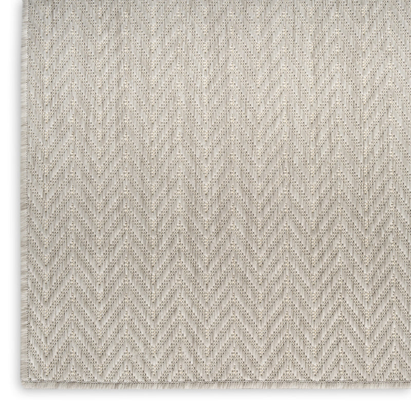 Light gray indoor outdoor area rug with repeating zigzag chevron pattern