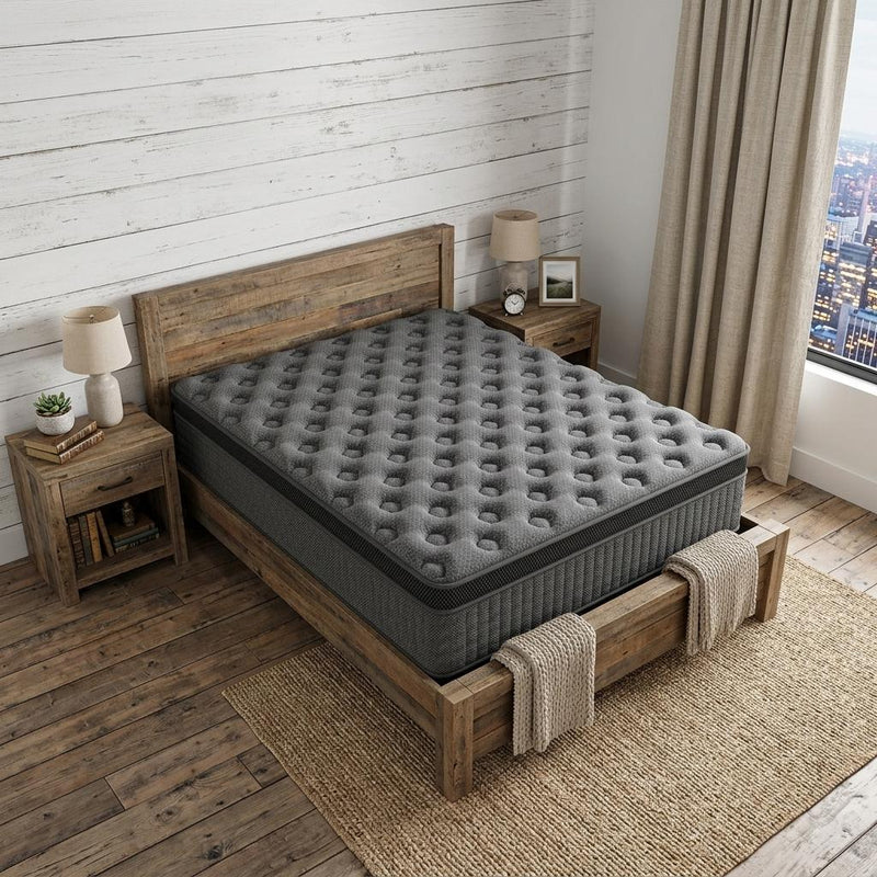 Gray hybrid mattress with tufted comfort top on a wooden bed frame