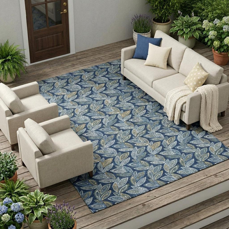 Botanical leaf area rug in navy, blue, and gold, placed on indoor wood flooring.