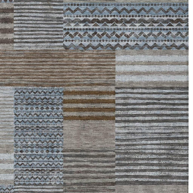 Rug close-up with horizontal gray stripes, tan and dark blocks, and a blue patterned stripe