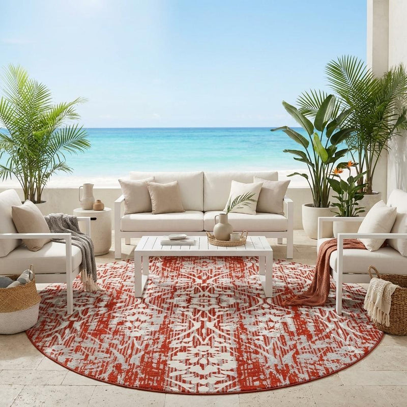 Round rust-red and cream damask area rug on patio floor, abstract lattice print