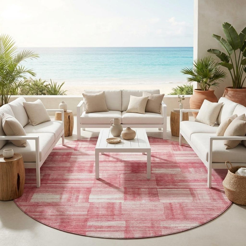 Round pink and ivory area rug with distressed patchwork pattern on the floor