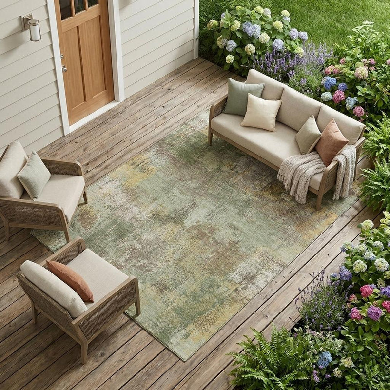 Olive green abstract area rug with washed pattern on a wooden outdoor deck.