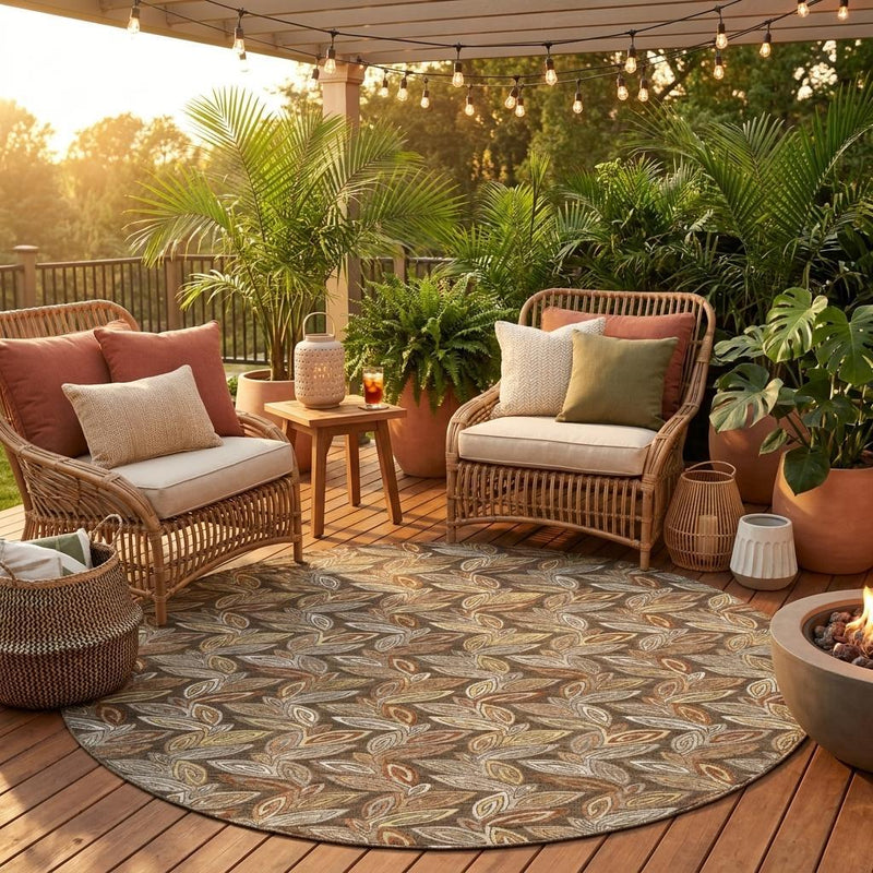Round botanical leaf area rug on an outdoor patio, taupe base with brown and olive accents