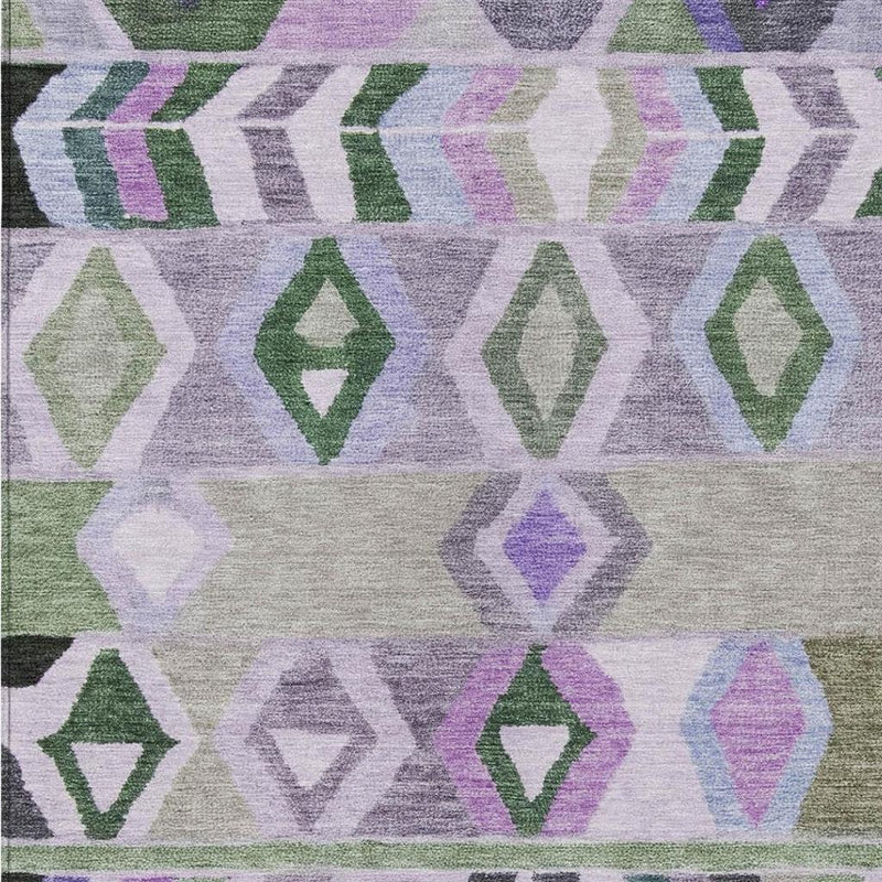 Close-up tribal area rug with lavender, green, and gray diamond patterns on light base