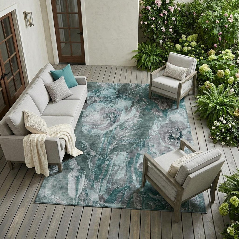 Teal and graphite floral area rug with distressed motif, placed on outdoor wood deck