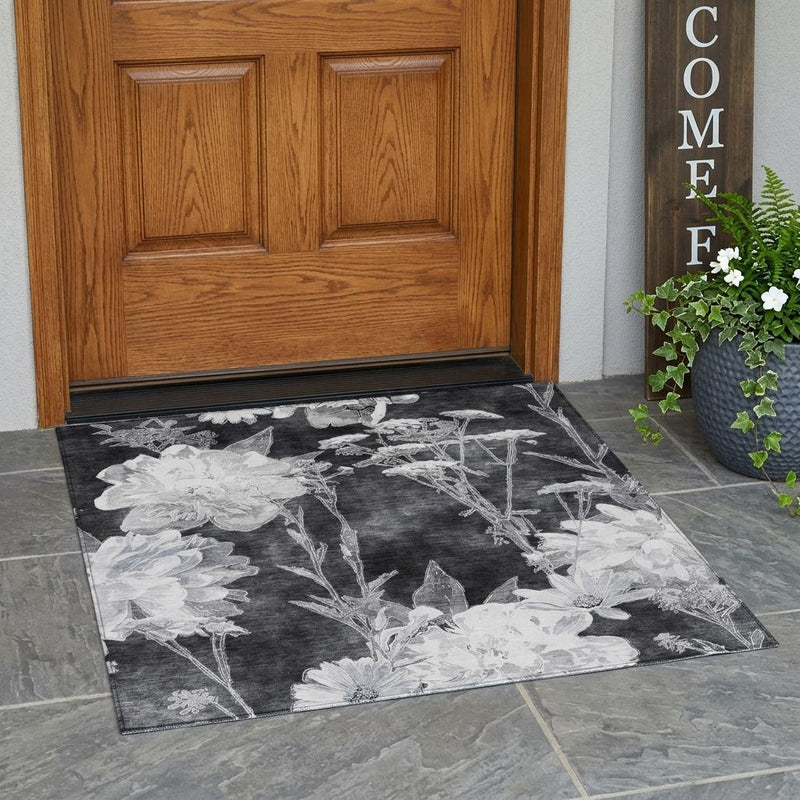 Charcoal area rug with large white flowers and thin stems, corner view on floor