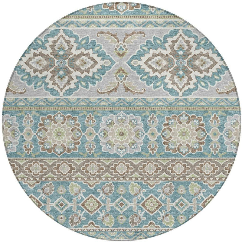 Round area rug featuring teal-blue stripes and tan, green, and cream floral motifs