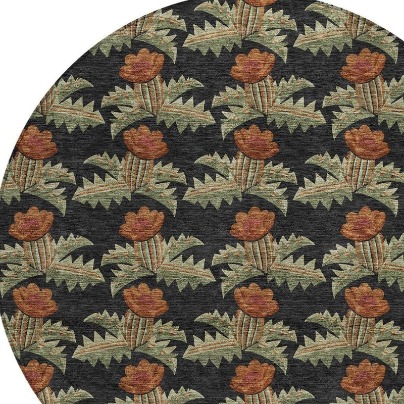 Top view of round rug showing black background with brown-orange florals and green details