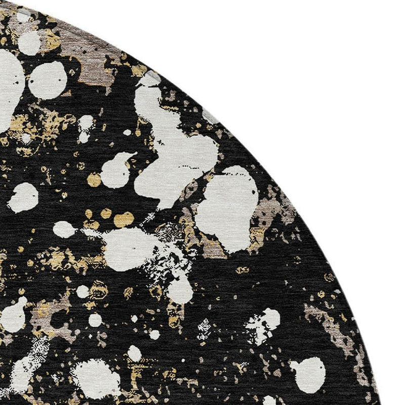 Round abstract area rug edge in black with white splatters and gold fleck accents