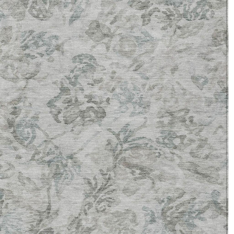 Textured close-up of light taupe area rug with faded teal floral pattern