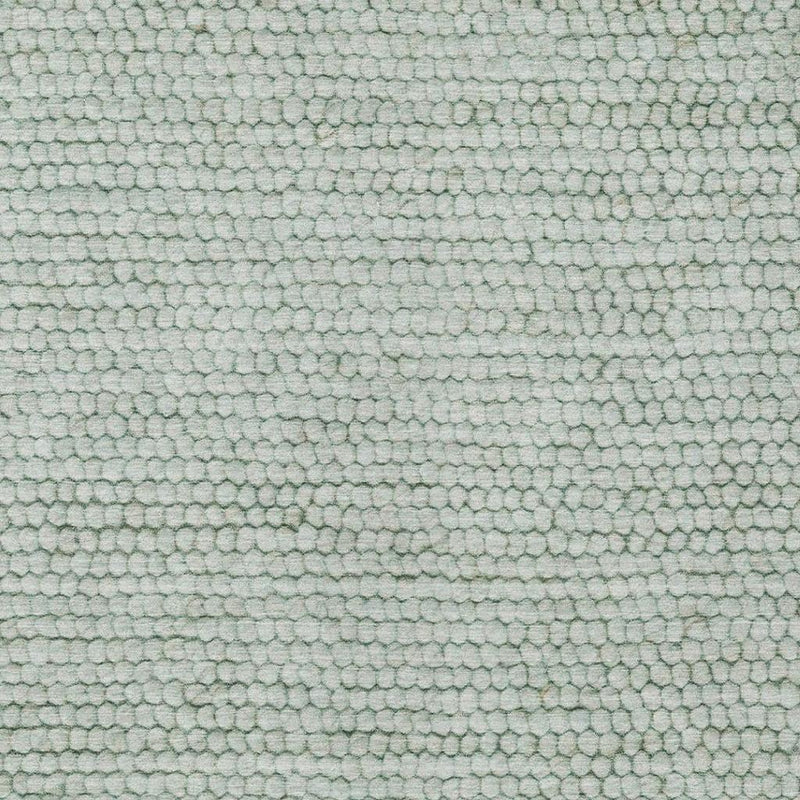 Close-up of textured rug surface in green and blue with pebble-like dots