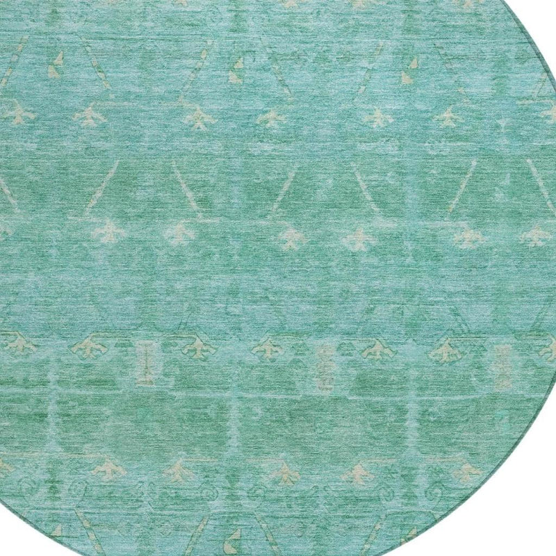 Close-up of round teal-green rug with repeating distressed tribal pattern
