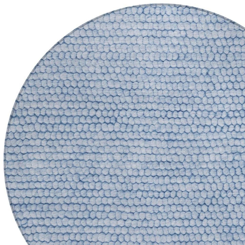 Blue round area rug edge with textured looped pebble pattern, close-up.