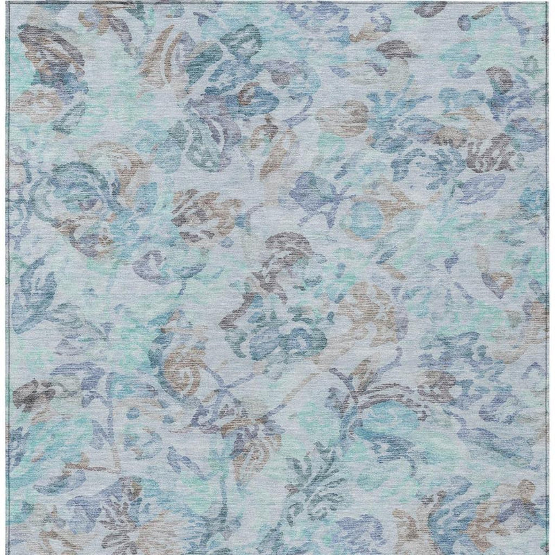 Light blue area rug with faded floral motif all over in silver and teal tones