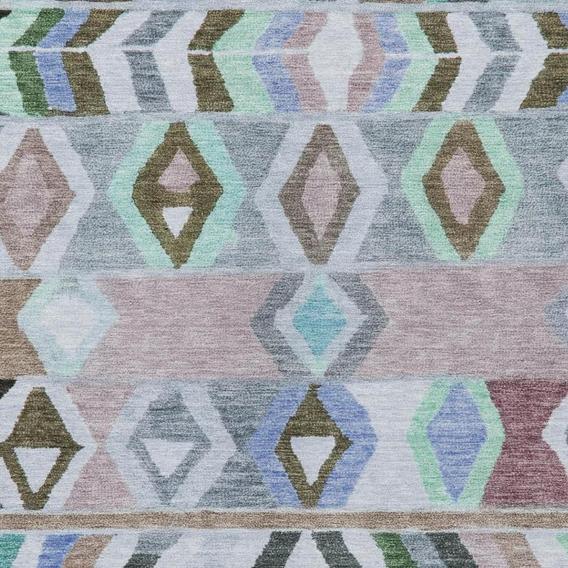 Beige area rug close-up with pastel diamonds, arrows, and chevrons in green and blue.