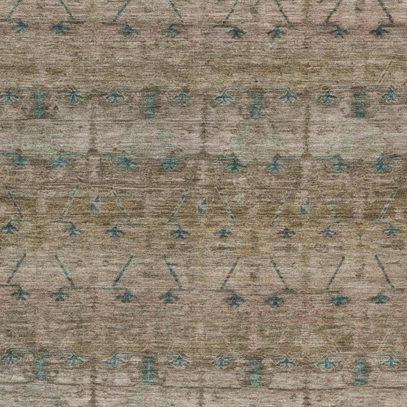 Close-up of taupe area rug showing teal arrow-like tribal motifs across the surface