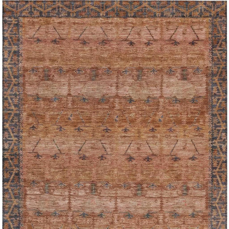 Rust-orange area rug with navy-blue tribal bands and worn textured weave.