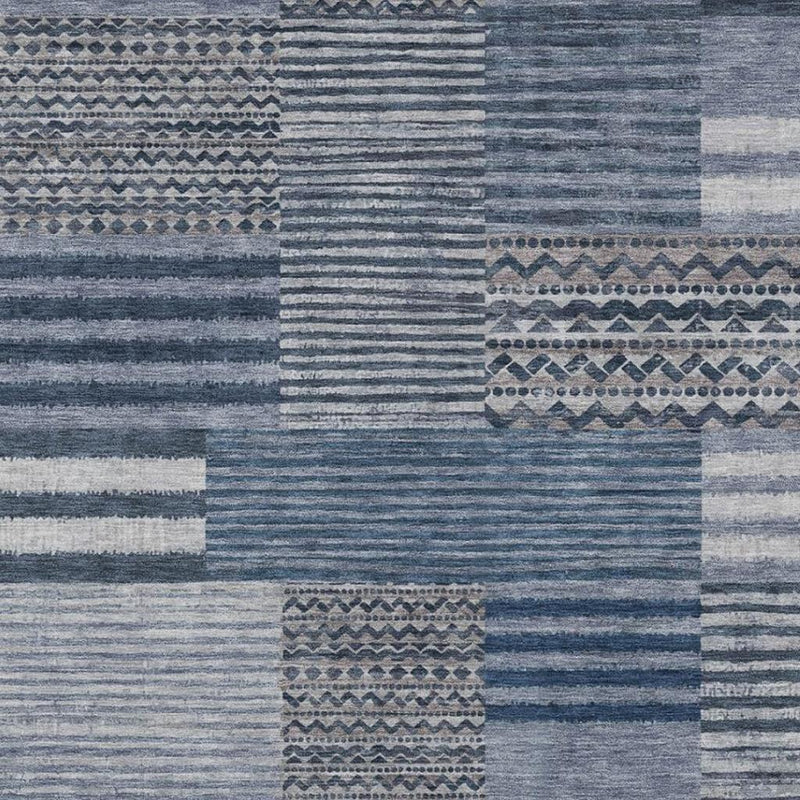 Close-up of blue and gray patchwork area rug with striped lines and medallion panel