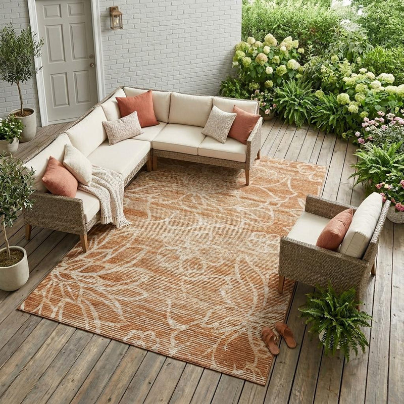 Orange and rust floral area rug laid on patio floor, surrounded by seating