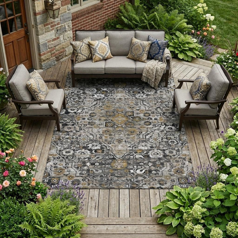 Gray and black floral medallion outdoor area rug on wooden patio, staged