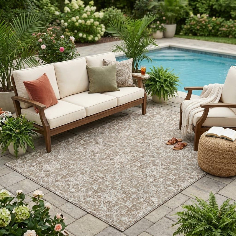 Beige and brown damask area rug laid outdoors with distressed ornate design