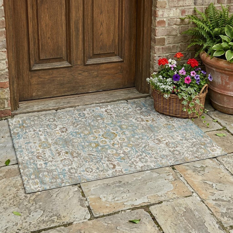 Floral medallion area rug in ivory, blue, and pewter laid on outdoor stone patio