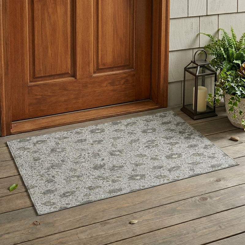 Silver and gray indoor/outdoor area rug with distressed floral pattern on wood floor