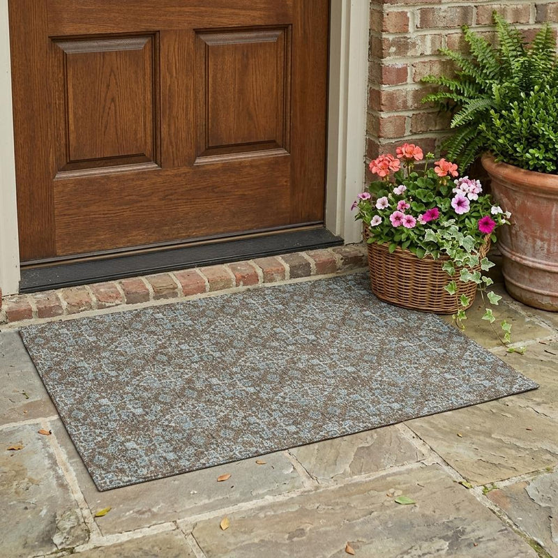 Outdoor damask area rug in brown and teal with ornate medallion pattern, on patio