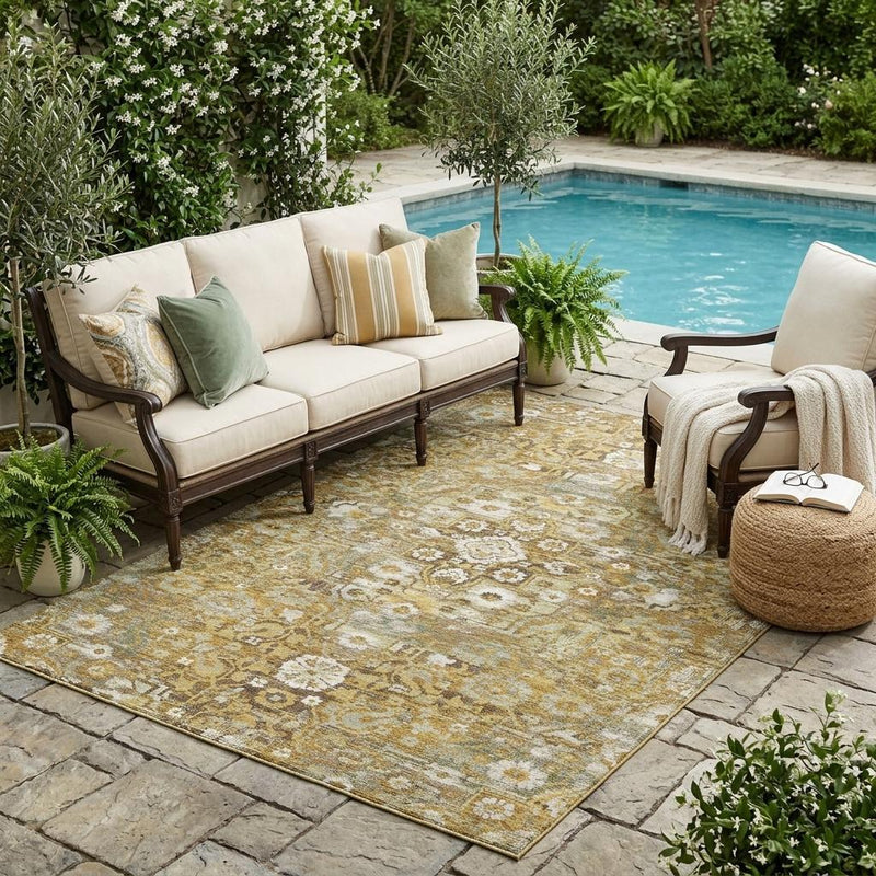Indoor outdoor area rug with distressed floral medallion pattern in gold, tan, and cream