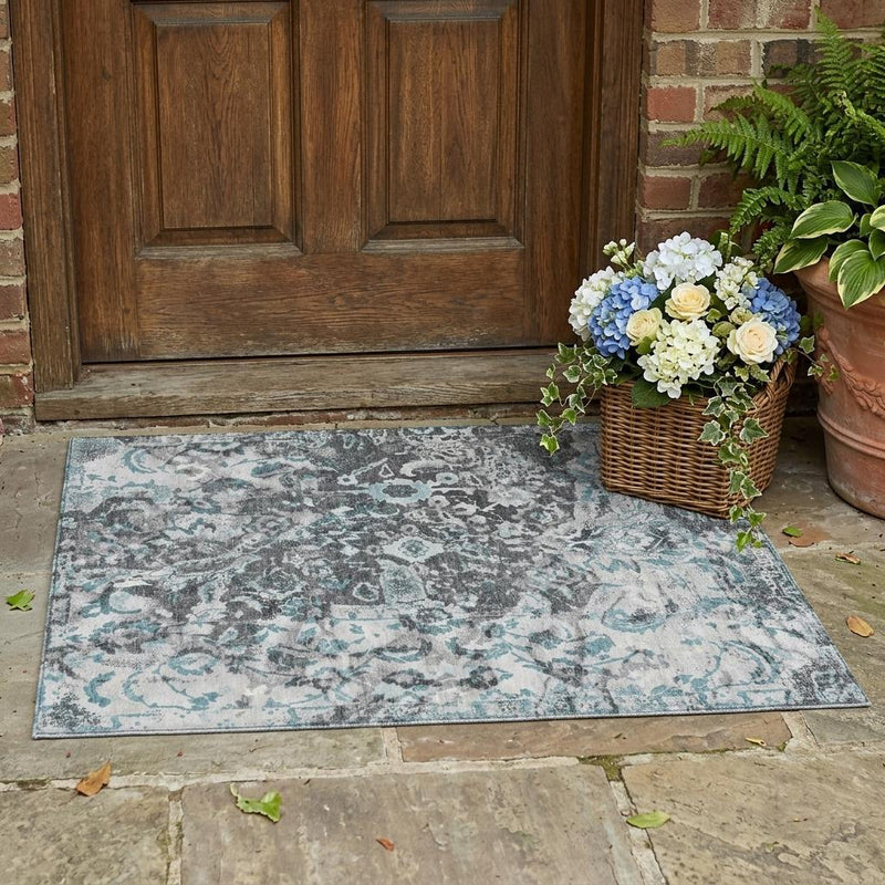 Floral area rug in silver, gray, and light blue shown outdoors