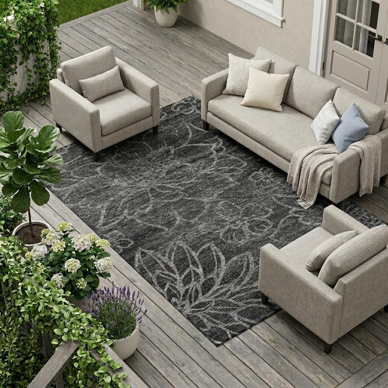 Indoor outdoor area rug with dark graphite floral pattern and textured flat weave.