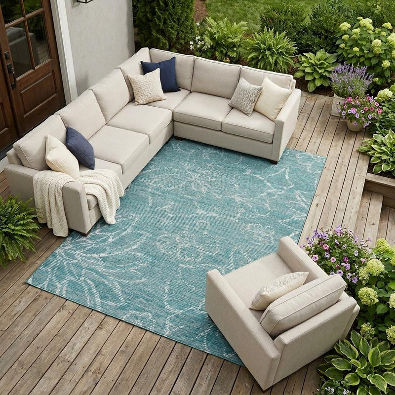 Teal blue outdoor area rug with light floral distressed pattern under patio seating