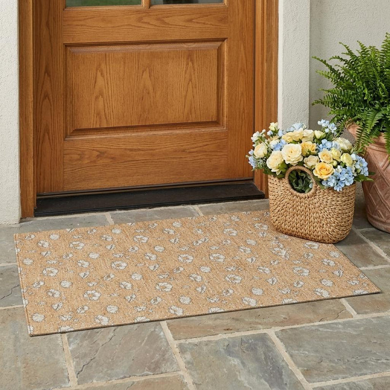 Copper orange floral area rug with light gray blossoms laid on stone tile