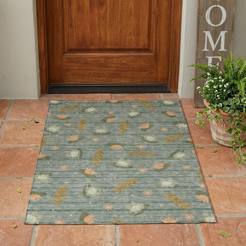 Botanical leaf area rug, blue-green with tan and orange prints, on terracotta tiles