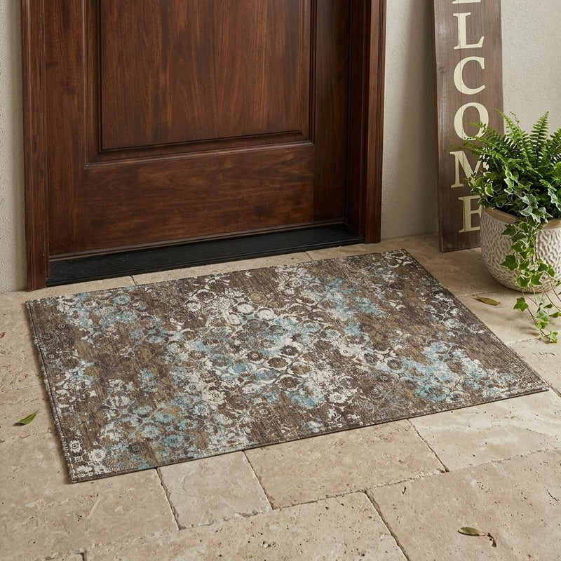 Brown and coffee washable area rug with blue floral medallion design on floor.