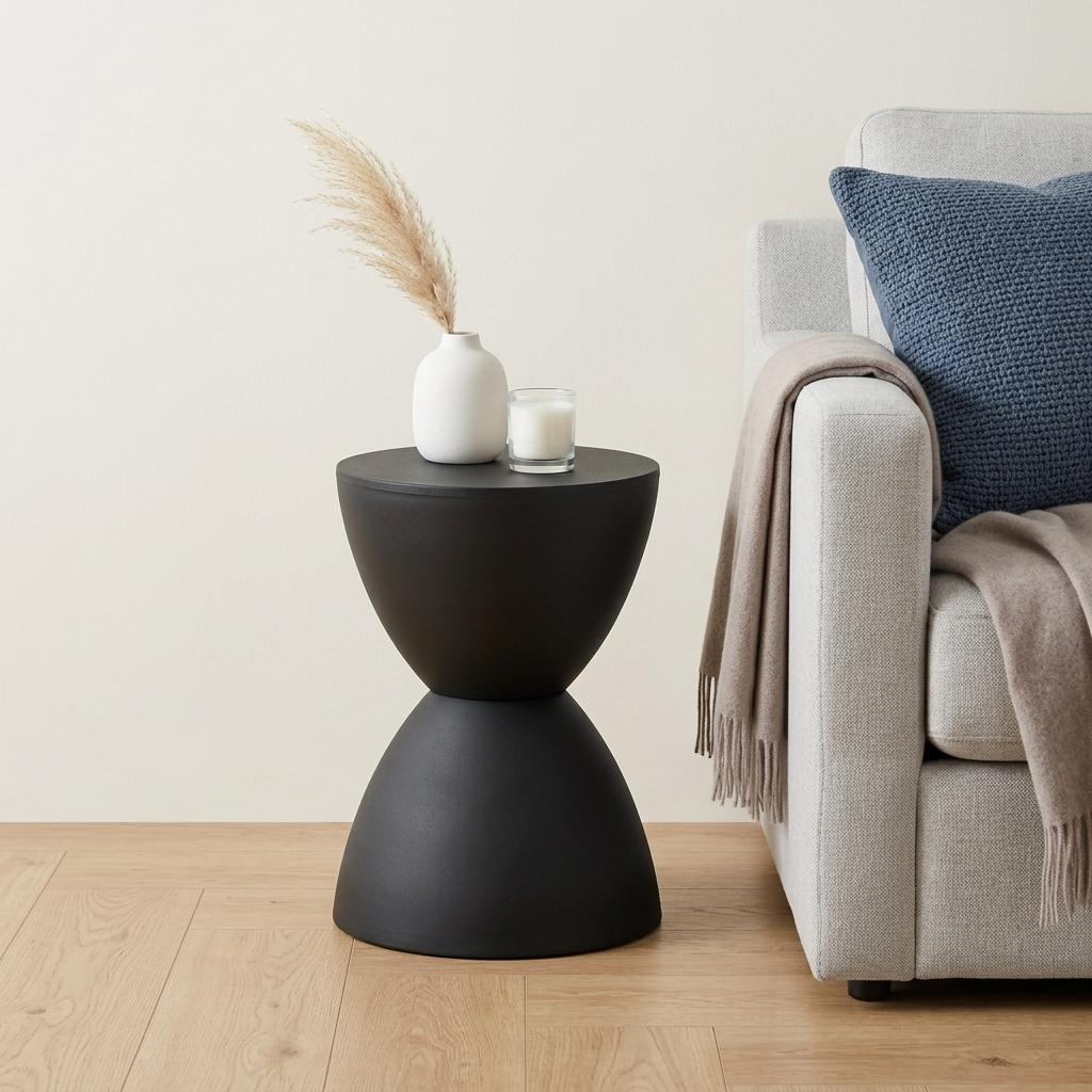 Black hourglass side table with round top and tapered pedestal base.