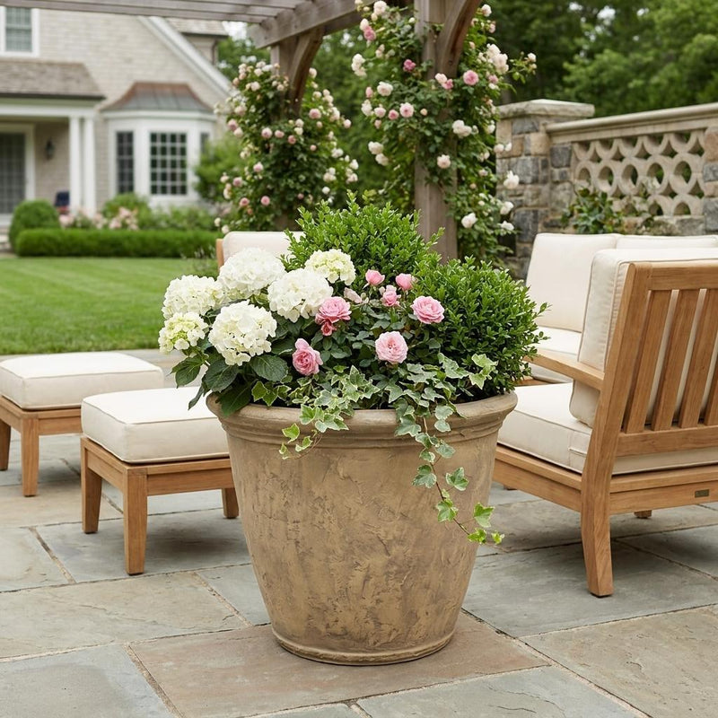 Beige round plastic planter pot with flowers on a patio