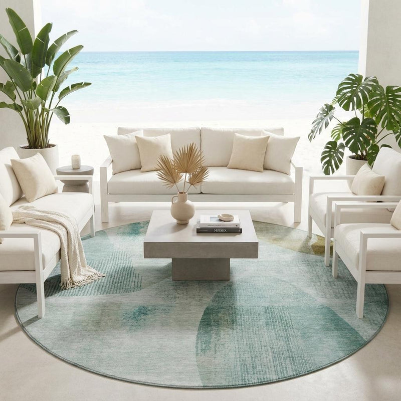 Round abstract geometric rug in teal and off-white, styled for indoor seating area.