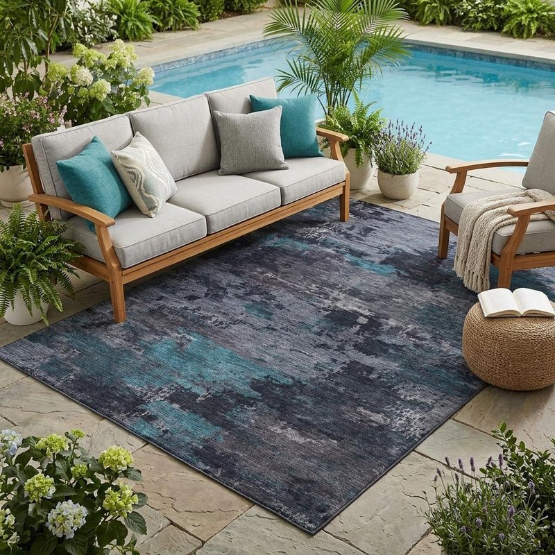 Indoor outdoor area rug with graphite base and teal-blue abstract wash design.