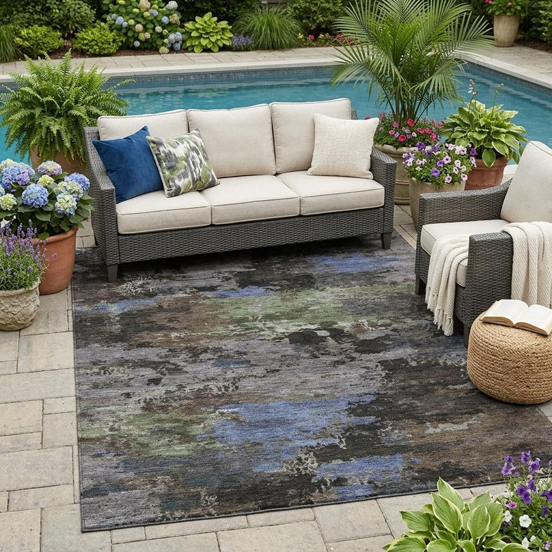 Abstract washable outdoor area rug under patio furniture with blue and gray distressed pattern.