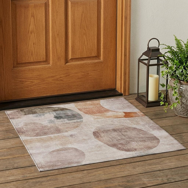 Abstract area rug laid out, beige base with copper-orange and brown block and oval shapes.