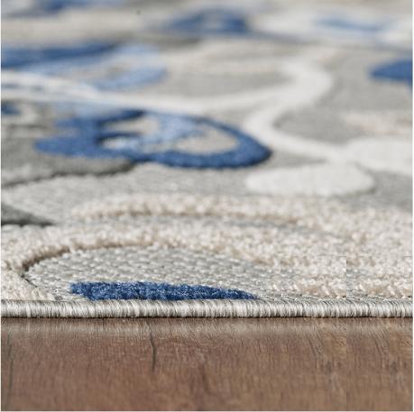 Indoor/outdoor area rug with blue floral motif and gray border, flatwoven edge view
