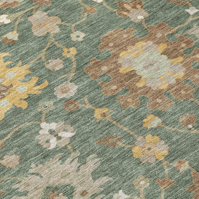 Close-up of green area rug with beige, tan, and cream floral motifs and distressed look.
