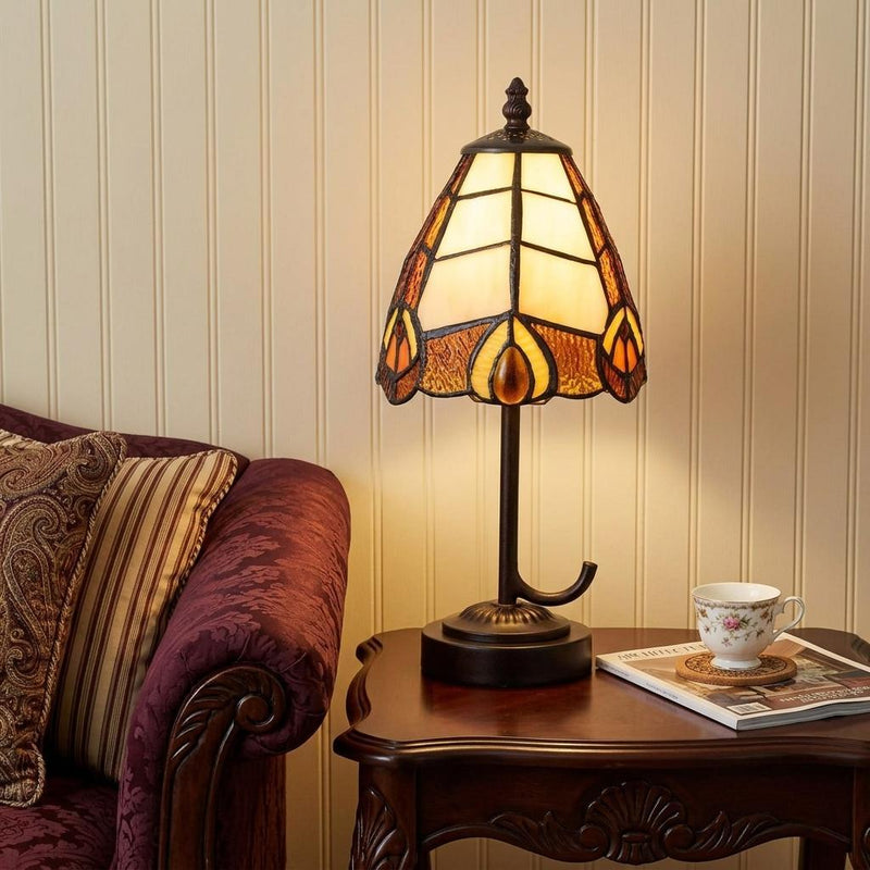 Bronze Tiffany-style table lamp with cone stained-glass shade on a wooden side table